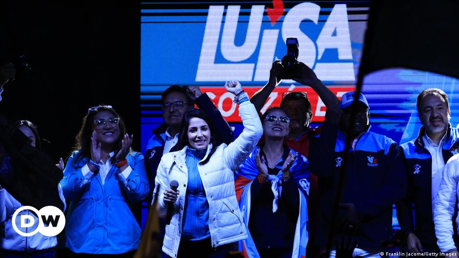 Armed soldiers in camouflage stand in front of a graffiti-covered wall