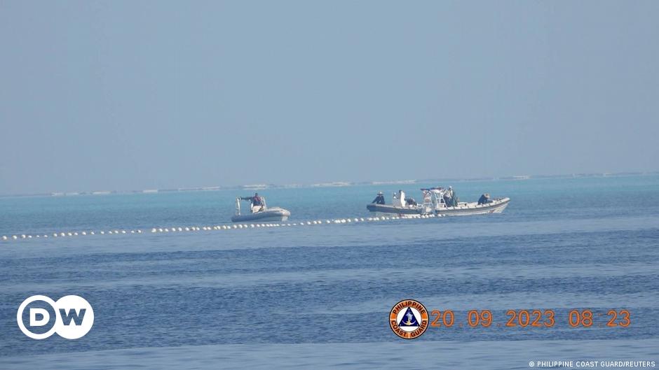 Boris Pistorius (left) sits at a long table with other delegates, with the German and Chinese flags between them