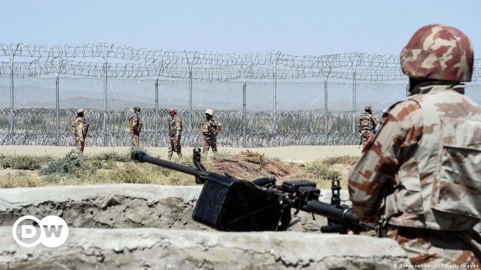 A woman holds her arm up in protest as a fire burns on a road