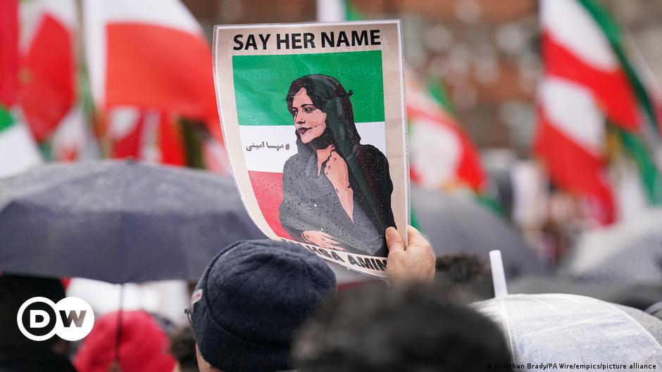 A man looks at a lantern a woman is holding with her hands.