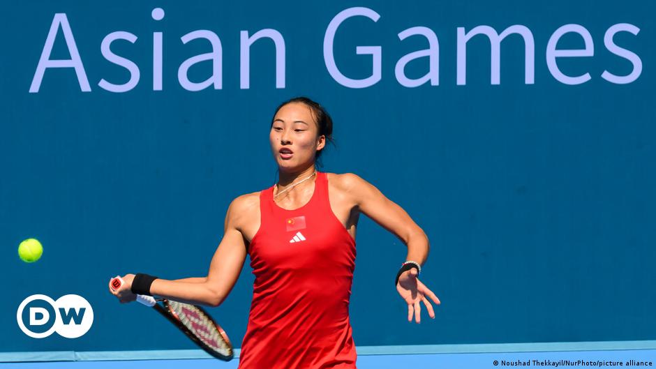 Katalin Kariko and Drew Weissman wearing masks and lab coats, looking at a computer