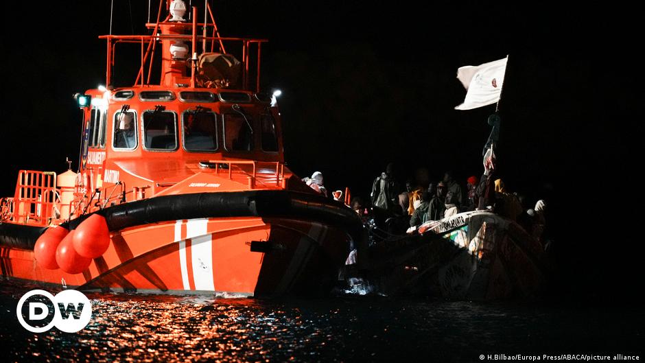 Migrants sit onboard a boat navigating in agitated waters