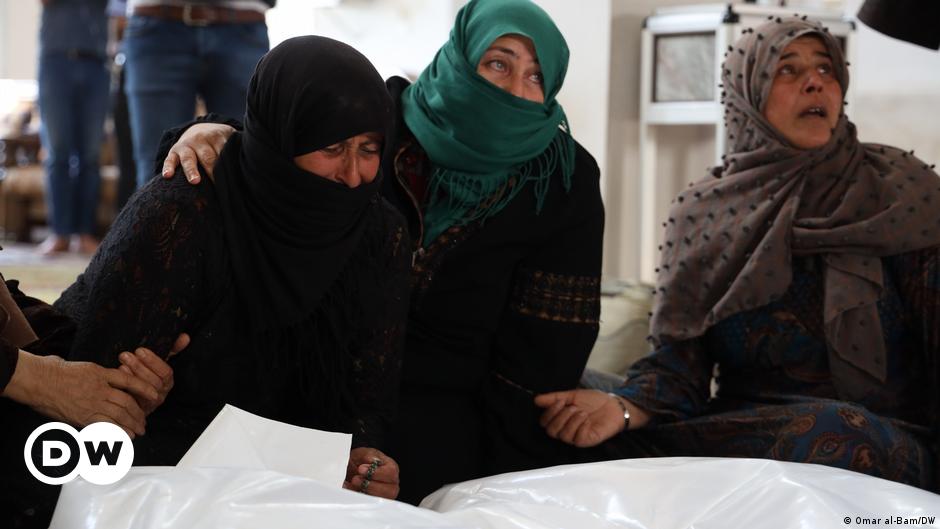 A man walks past banners depicting Syria's President Bashar al-Assad, near damaged buildings