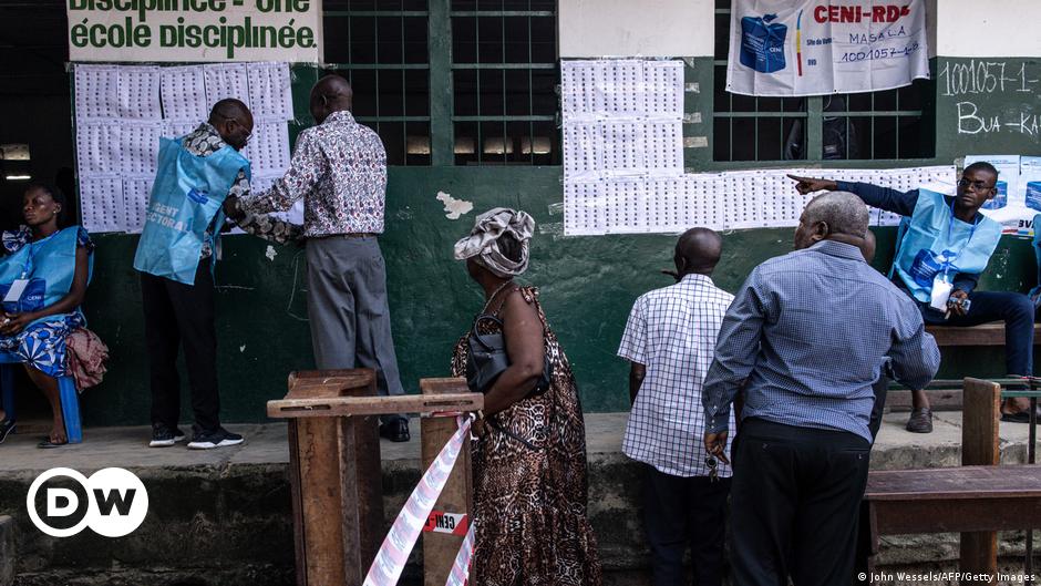 A person dressed in a red T-shirt places a ballot in a ballot box