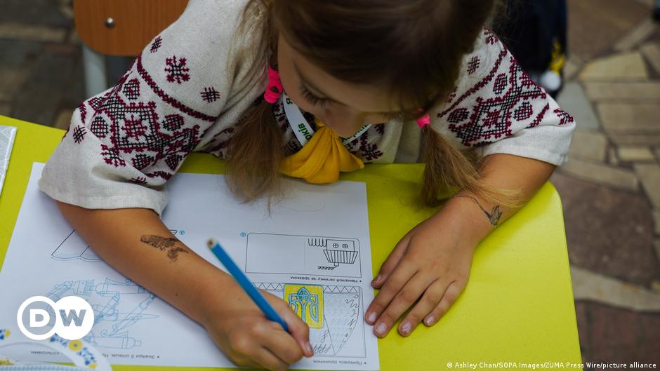 A Ukrainian soldier holds a weapons as he walks down a muddy road that has snow lying on both sides.