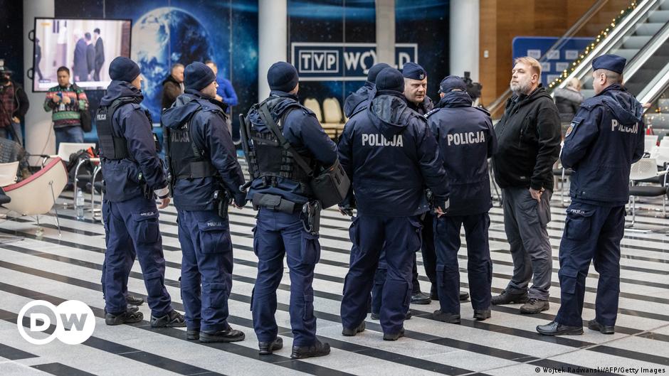 A gray-haired man (Jacek Lepiarz) stands in front of bookcases full of books