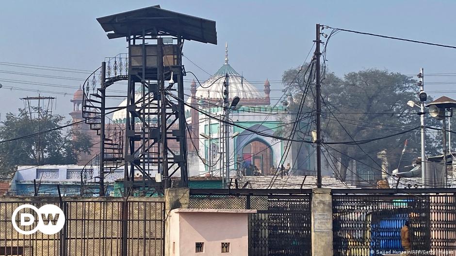 A worker removes broken glass from a window of a restaurant which was partially vandalized