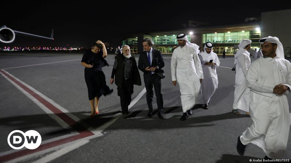 Empty classroom in an Afghan school for girls, with a woman clearing off the white board at the front of the class