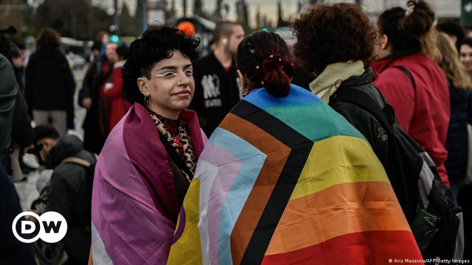 Film still ORFEAS2021, Mezzo-soprano Diamanti Kritsotaki , man with black hair sits, wearing bloodied transparent plastic wrap