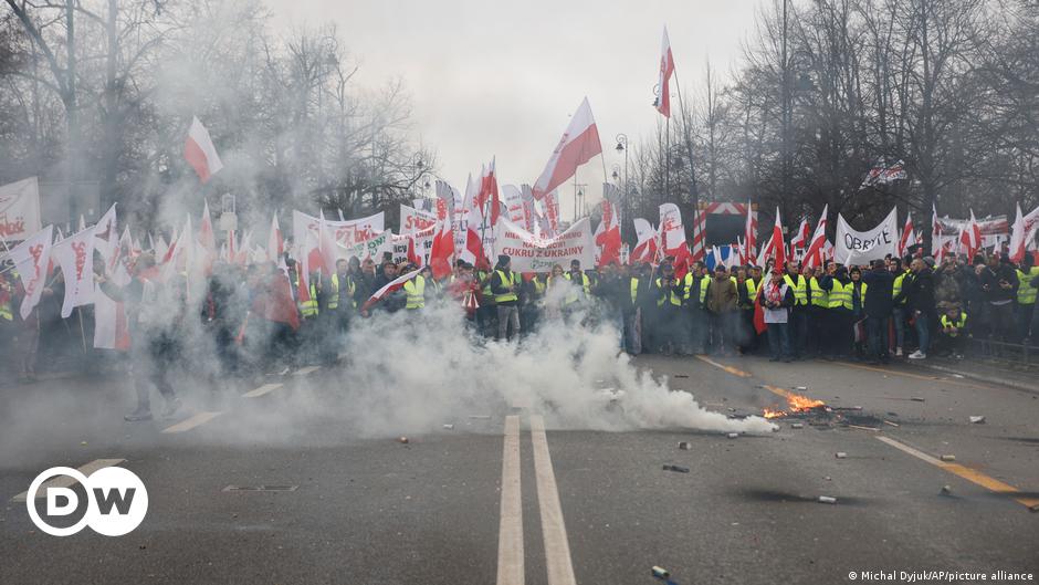 A gray-haired man (Jacek Lepiarz) stands in front of bookcases full of books