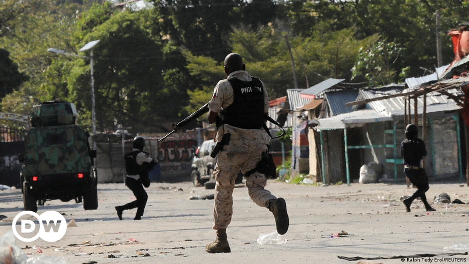 A police officer lies on the ground and aims a rifle during clashes with gang members in Port-au-Prince, Haiti, Friday, March 1, 2024.