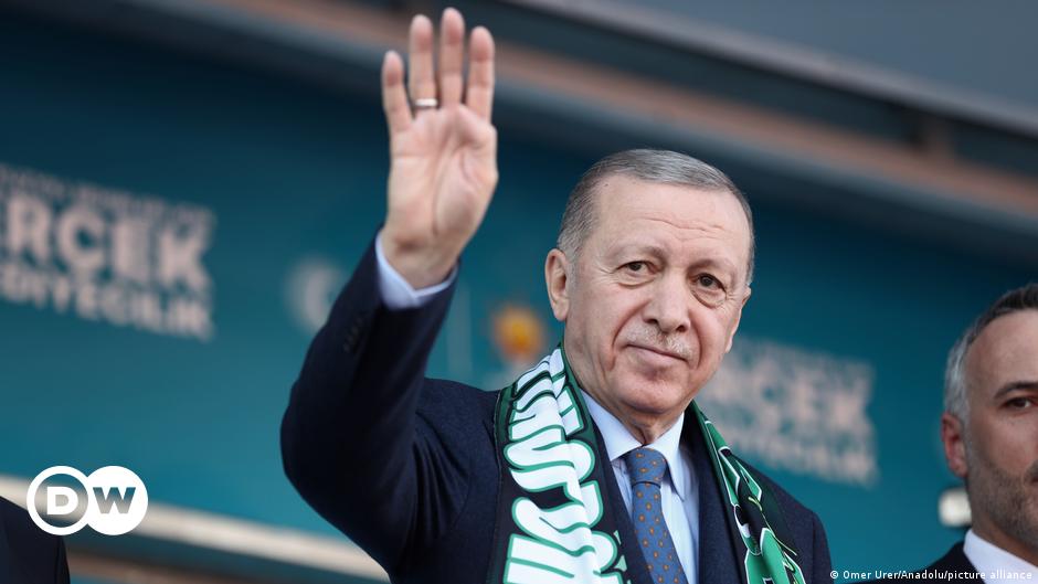 Elmas Topcu, sitting next to a bookcase full of books